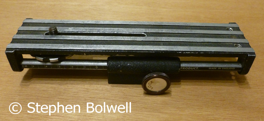 A small focusing system on rails that I only use for very small subjects - focus is achieved by turning the wheel to move the camera and lens backwards and forwards, consequently there is no need to readjust the focus ring on the lens. Made in Britain is etched on the side - so it must be old!